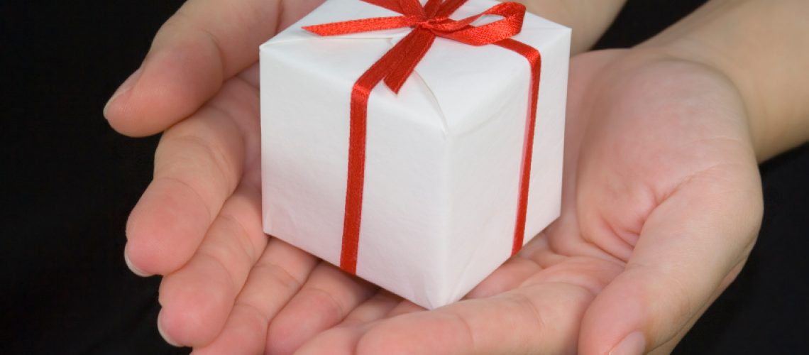 Hands holding a gift box isolated on black background